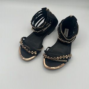 Steve Madden black and gold sandal with gold grommet and chains. Zipper back